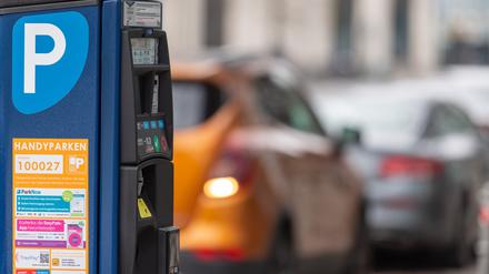 Ein Parkscheinautomat steht am Straßenrand in der Innenstadt. Im Hintergrund parken Autos auf der Straße. (Symbolbild)