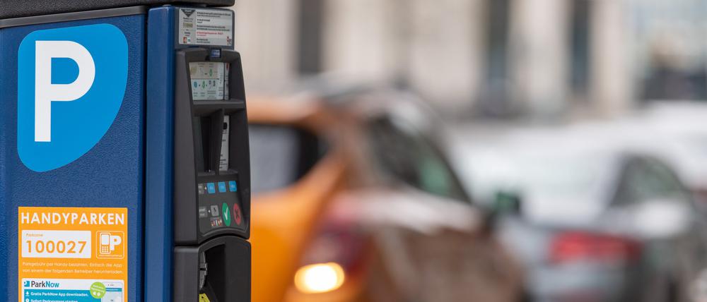 Ein Parkscheinautomat steht am Straßenrand in der Innenstadt. Im Hintergrund parken Autos auf der Straße. (Symbolbild)