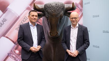 Sander van der Laan (l), CEO von Douglas und Finanzchef (CFO) Mark Langer stehen beim Börsengang der Douglas AG vor der Börse an der Bullen-Skulptur. 