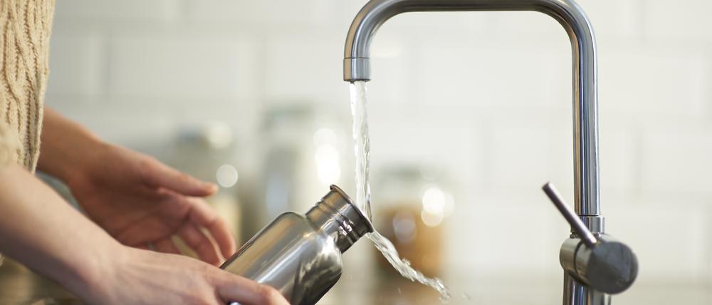 Eine Frau füllt eine Wasserflasche (Symbolbild).