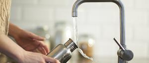 Eine Frau füllt eine Wasserflasche (Symbolbild).