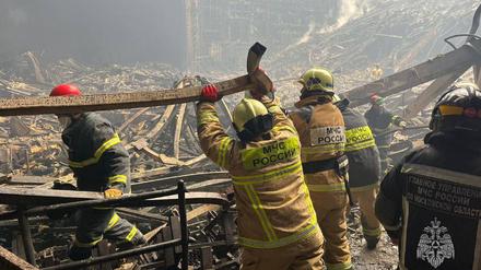 Feuerwehrleute arbeiten im Innern der ausgebrannten Konzerthalle.