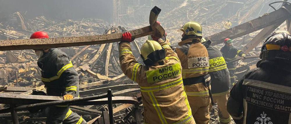 Feuerwehrleute arbeiten im Innern der ausgebrannten Konzerthalle.