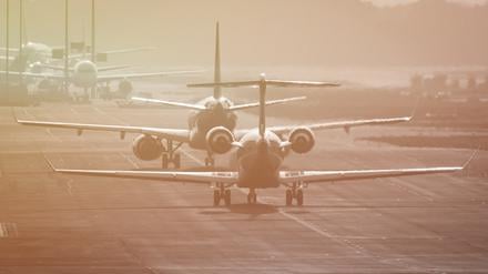 Flugzeuge rollen auf dem Flughafen Frankfurt im letzten Sonnenlicht des Tages über die Rollbahn.