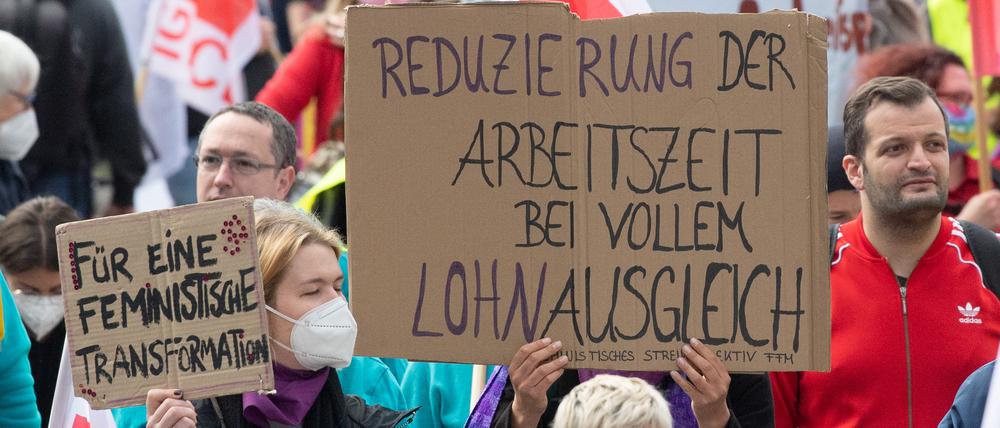 „Reduzierung der Arbeitszeit bei vollem Lohnausgleich“ steht auf dem Plakat einer Frau bei der Mai-Kundgebung der Gewerkschaften in Frankfurt am Main.