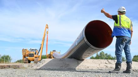 Eine Baumaschine verlegt Rohre für die LNG-Anbindung. Polier (Rohrleitungsbau) Bernd Kampen kontrolliert die Baustelle. Für den Import von Gas ist auch der Anschluss an das deutsche Gasnetz und damit die Möglichkeit zum Weitertransport der Energie elementar. 
