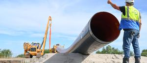 Eine Baumaschine verlegt Rohre für die LNG-Anbindung. Polier (Rohrleitungsbau) Bernd Kampen kontrolliert die Baustelle. Für den Import von Gas ist auch der Anschluss an das deutsche Gasnetz und damit die Möglichkeit zum Weitertransport der Energie elementar. 
