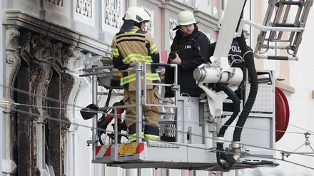 Feuerwehrmänner stehen vor einem Mehrfamilienhaus in Solingen, in dem es gebrannt hat.