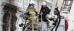 Feuerwehrmänner stehen vor einem Mehrfamilienhaus in Solingen, in dem es gebrannt hat.