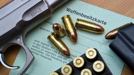  Eine Kaliber 9 mm Pistole, Patronen und ein Magazin liegen auf einer Waffenbesitzkarte. 