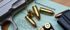 Eine Kaliber 9 mm Pistole, Patronen und ein Magazin liegen auf einer Waffenbesitzkarte.