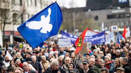 ARCHIV - Menschen nehmen 2023 am Ostermarsch in Berlin-Wedding unter dem Motto «Den Frieden gewinnen · nicht den Krieg!» mit einer Flagge mit einer Friedenstaube teil. Auch in diesem Jahr steht der Ukraine-Krieg im Zentrum (zu dpa: «Ostermarsch will Zeichen gegen Krieg setzen - Verhandlungen gefordert») Foto: Fabian Sommer/dpa +++ dpa-Bildfunk +++
