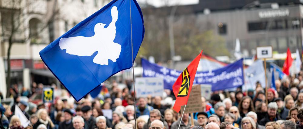 ARCHIV - Menschen nehmen 2023 am Ostermarsch in Berlin-Wedding unter dem Motto «Den Frieden gewinnen · nicht den Krieg!» mit einer Flagge mit einer Friedenstaube teil. Auch in diesem Jahr steht der Ukraine-Krieg im Zentrum (zu dpa: «Ostermarsch will Zeichen gegen Krieg setzen - Verhandlungen gefordert») Foto: Fabian Sommer/dpa +++ dpa-Bildfunk +++