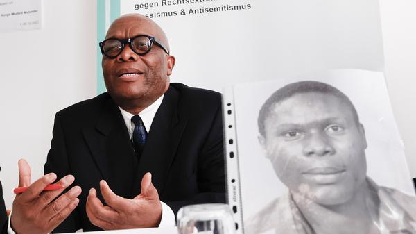 Mutombo Mansamba, sitzt hinter einem Bild seines gestorbenen Bruders Kupa Ilunga Medard Mutombo, bei einer Pressekonferenz in der Beratungsstelle ReachOut zum Fall von Kupa Ilunga Medard Mutombo, der drei Wochen nach einem Polizeieinsatz ums Leben kam. 