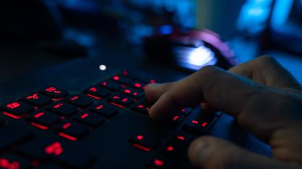 Ein Mann sitzt am Rechner und tippt auf einer Tastatur. 