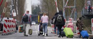 Ukrainische Flüchtlinge verlassen mit ihrem Gepäck eine Flüchtlingsunterkunft. 