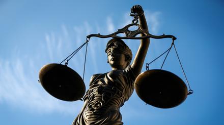  Eine Statue der Justitia hält eine Waage in der Hand.  