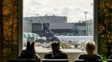 Fluggäste schauen am Rhein-Main-Flughafen auf das Vorfeld mit einer Lufthansamaschine. 