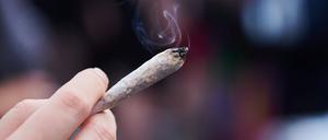 Eine Frau hält einen Joint in der Hand.