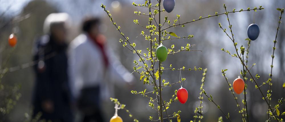 Zwei Menschen laufen an aufgehängten Ostereiern vorbei im Britzer Garten. (Symbolbild)