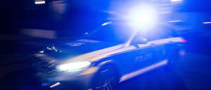 Ein Polizeifahrzeug fährt mit Blaulicht an einem Gebäude vorbei
