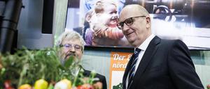 Kein Gras weit und breit: Ministerpräsident Dietmar Woidke (rechts, SPD) und Landwirtschaftsminister Axel Vogel (Grüne) stehen hinter Kunstblumen in der Brandenburg-Halle bei der Grünen Woche in Berlin.