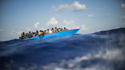 Migranten sitzen in einem Holzboot im Mittelmeer (Symbolbild).