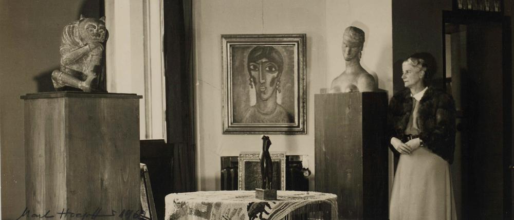 Hanna Bekker vom Rath 1946 mit Teilen ihrer Sammlung, darunter der antike chinesische Flussgeist, ein Bildnis von Alexej von Jawlensky, die gewebte Tischdecke von Ida Kerkovius mit einer Kleinskulptur von Alexander Archipenko darauf und eine Büste von Wilhelm Lehmbruck.