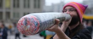 01.04.2024, Sachsen, Leipzig: Ein Teilnehmer einer Kundgebung hält einen überdimensionierten Joint in den Händen. Ab dem 1. April 2024 ist Erwachsenen ab 18 Jahren der Besitz von 25 Gramm im öffentlichen Raum erlaubt. Foto: Sebastian Willnow/dpa +++ dpa-Bildfunk +++