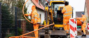 Arbeiter sind mit Bagger und Spaten an einer Straße mit der Erdverlegung von Glasfaserkabeln beschäftigt. +++ dpa-Bildfunk +++
Glasfas
