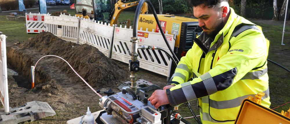 Ein Arbeiter verlegt Glasfaserkabel in Berlin.