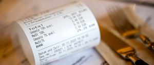 Eine Rechnung mit Umsatzsteuer und Mehrwertsteuer liegt auf der Speisekarte eines Restaurants.