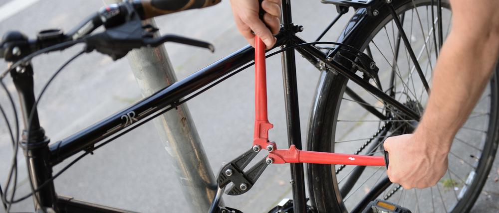 Ein Mann versucht mit einem Bolzenschneider, ein Fahrradschloss aufzubrechen (gestellte Szene). 