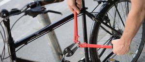 Ein Mann versucht mit einem Bolzenschneider, ein Fahrradschloss aufzubrechen (gestellte Szene). 