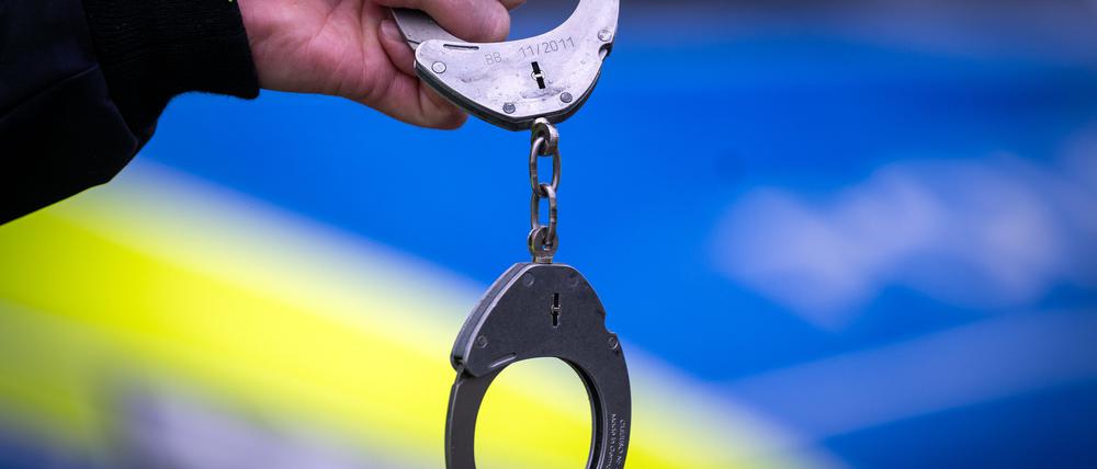 Ein Polizist hält Handschellen (Symbolbild). 