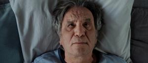 Ein Mann liegt mit offenen Augen im Bett.