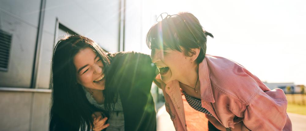 Manchmal kann man einfach nicht anders: Zwei junge Frauen krümmen sich vor Lachen.