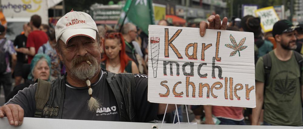 Ein Mann hält auf der Hanfparade 2023 am Berliner Alexanderplatz ein Schild mit der Aufschrift „Karl mach schneller“