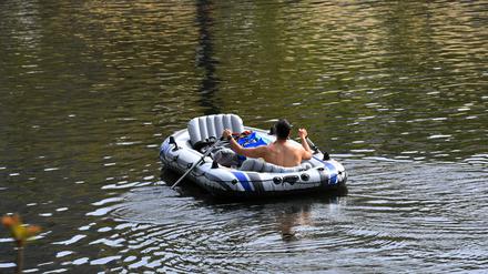 Ein Mann paddelt mit einem Schlauchboot auf dem Landwehrkanal. 