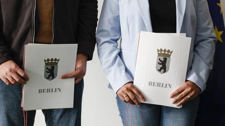 Eingebürgerte zeigen ihre Urkunden nach einer Feier bei der Zentralen Einbürgerungsstelle des Landesamtes für Einwanderung.