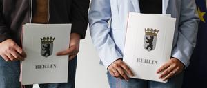 Eingebürgerte zeigen ihre Urkunden nach einer Feier bei der Zentralen Einbürgerungsstelle des Landesamtes für Einwanderung.