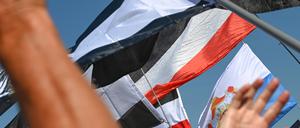 19.08.2023, Sachsen-Anhalt, Magdeburg: Reichsflaggen werden auf dem Magdeburger Domplatz zu einer Reichsbürgerkundgebung hochgehalten.