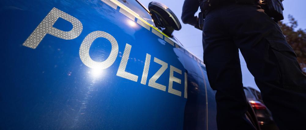 Eine Polizistin steht neben einem Polizeifahrzeug. 