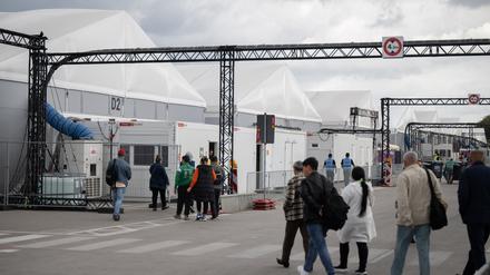 Bewohner und Mitarbeiter gehen im Ankunftszentrum am ehemaligen Flughafen Tegel in Richtung der Leichtbauhallen. (Archivbild)