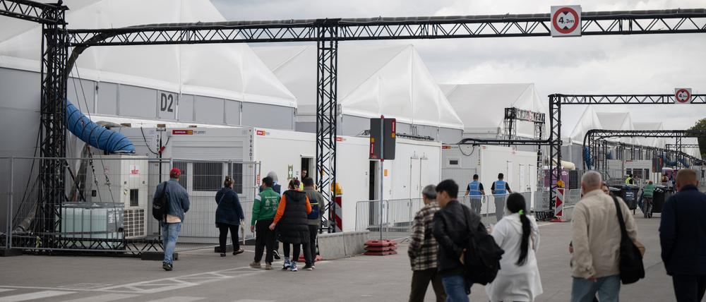 Bewohner und Mitarbeiter gehen im Ankunftszentrum am ehemaligen Flughafen Tegel in Richtung der Leichtbauhallen.
