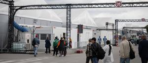 Bewohner und Mitarbeiter gehen im Ankunftszentrum am ehemaligen Flughafen Tegel in Richtung der Leichtbauhallen. (Archivbild)