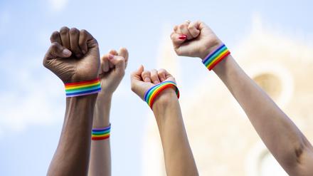 Hände mit queeren Armbändern fordern LGBTIQ-Rechte ein.