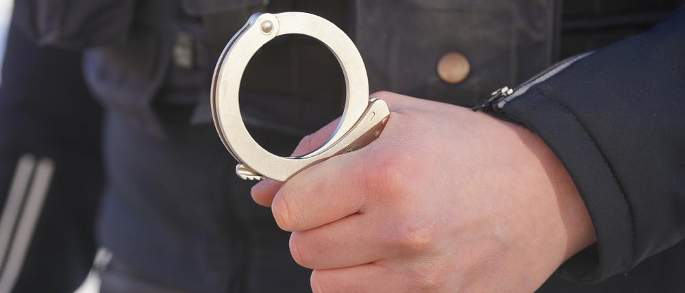 ARCHIV - 18.01.2024, Mecklenburg-Vorpommern, Schwerin: ILLUSTRATION - Ein Polizist hält Handschellen in der Hand. (zu dpa: «Mann soll in Leipzig mehrere Einbrüche begangen haben - Haftbefehl») Foto: Marcus Brandt/dpa +++ dpa-Bildfunk +++