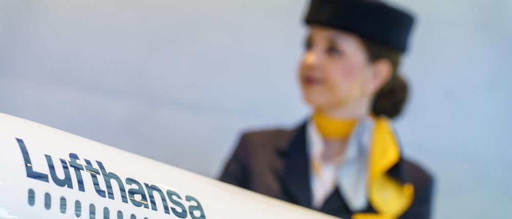 Eine Flugbegleiterin steht hinter einem Modell einer Lufthansamaschine.
