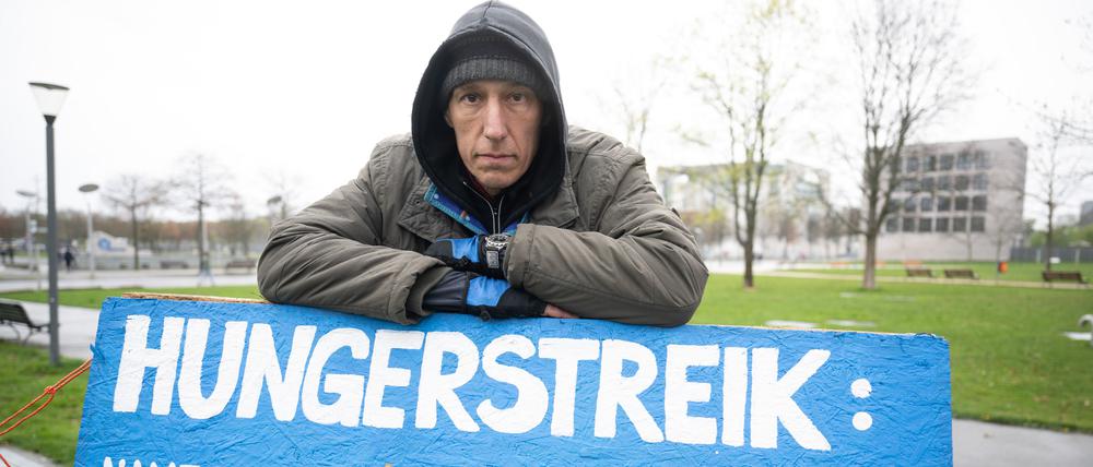 Aktivist Wolfgang Metzeler-Kick, der sich seit dem 7. März im Hungerstreik befindet, steht in einem Zeltlager im Spreebogenpark hinter einem Schild, auf dem die Anzahl seiner Tage im Hungerstreik markiert ist